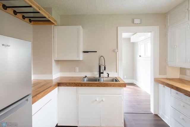 kitchen featuring hardwood / wood-style flooring, sink, fridge, and white cabinets