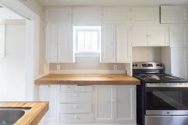 kitchen with butcher block counters, stainless steel range, and white cabinets