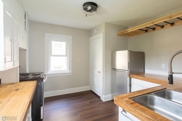 kitchen featuring a textured ceiling, dark hardwood / wood-style floors, stainless steel refrigerator, sink, and butcher block counters