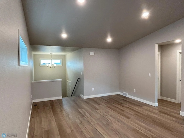 unfurnished room featuring wood-type flooring and an inviting chandelier