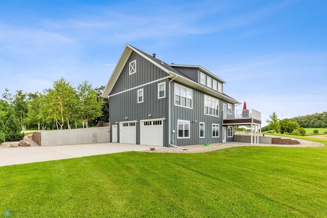 rear view of house with a balcony, a garage, and a lawn