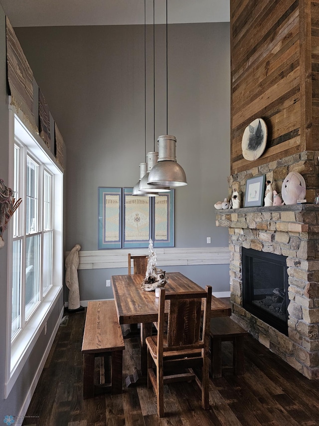 dining room with dark wood-type flooring and a stone fireplace