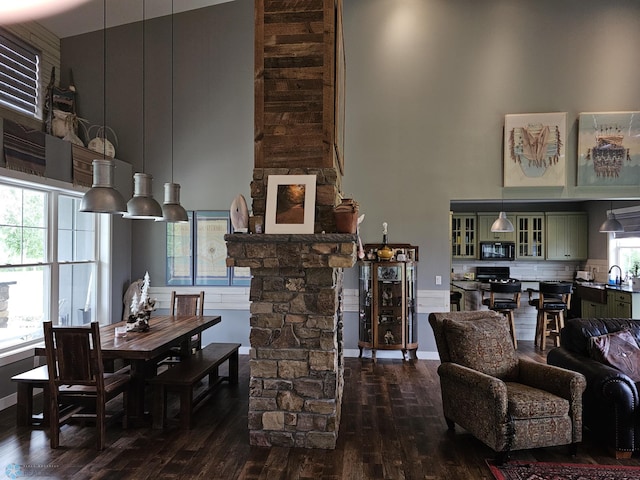 living room with dark wood-type flooring, plenty of natural light, and a high ceiling