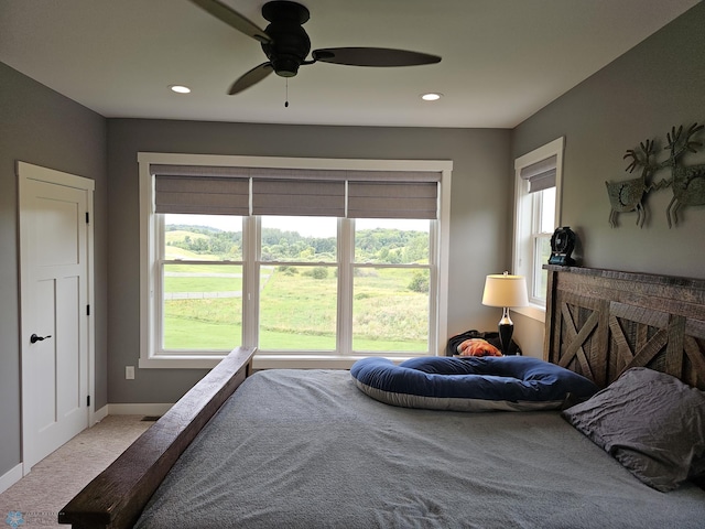 carpeted bedroom with multiple windows and ceiling fan