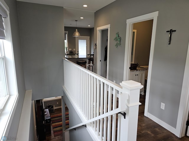 hallway with dark wood-type flooring and a healthy amount of sunlight