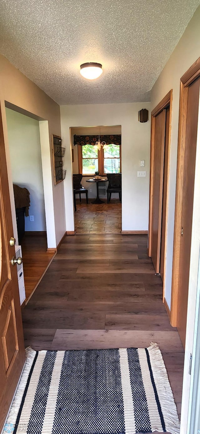 corridor with a textured ceiling and dark hardwood / wood-style floors