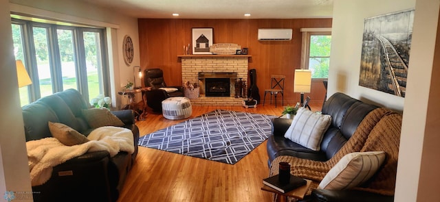 living room featuring an AC wall unit, a brick fireplace, and hardwood / wood-style flooring