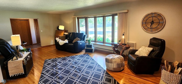 living room featuring a textured ceiling, a baseboard radiator, and hardwood / wood-style floors