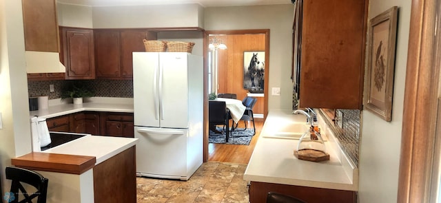 kitchen featuring light hardwood / wood-style floors, sink, white fridge, stove, and decorative backsplash