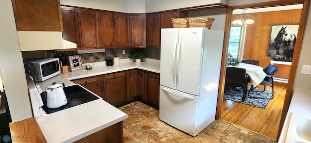 kitchen with a notable chandelier, dark brown cabinetry, white appliances, and hardwood / wood-style flooring