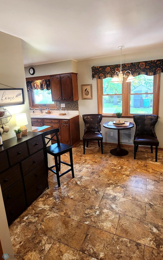 kitchen featuring pendant lighting, tasteful backsplash, dark brown cabinets, and a notable chandelier