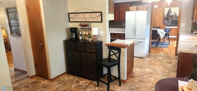 kitchen featuring a kitchen breakfast bar, light hardwood / wood-style flooring, backsplash, sink, and white refrigerator