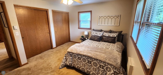 bedroom with two closets, ceiling fan, and carpet