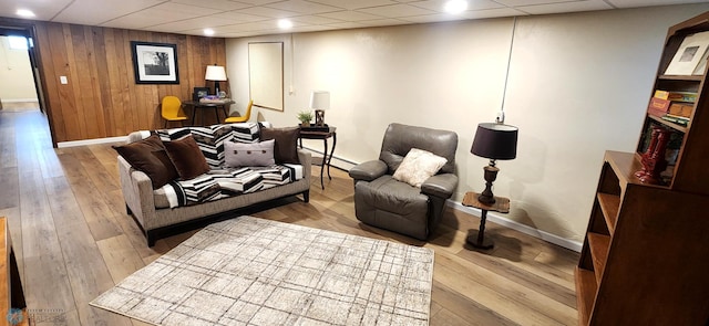 living room featuring wood walls, a paneled ceiling, light hardwood / wood-style floors, and a baseboard heating unit