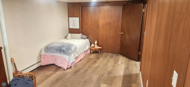 bedroom featuring a baseboard heating unit, a closet, and light wood-type flooring