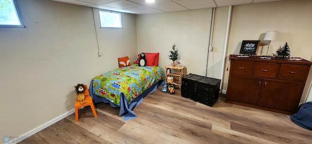 bedroom with light wood-type flooring and a drop ceiling