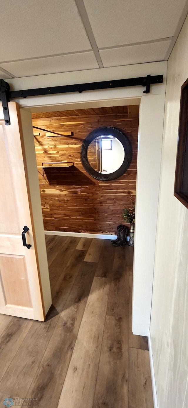 hallway featuring a barn door, wood walls, and wood-type flooring