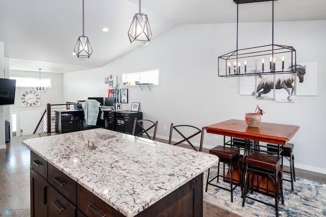 kitchen with lofted ceiling, a kitchen island, dark hardwood / wood-style floors, and a chandelier