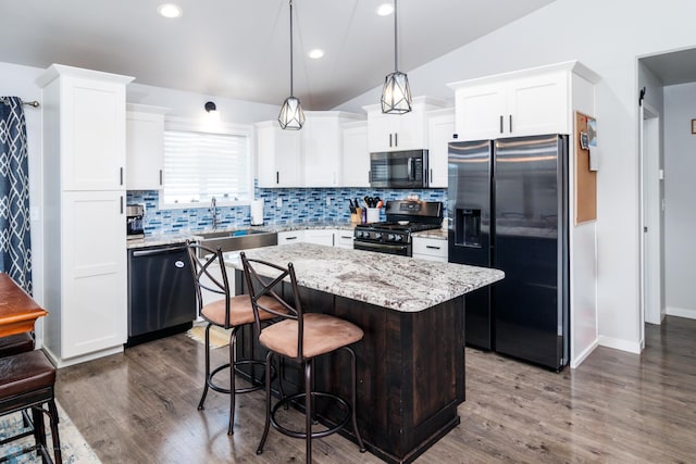 kitchen featuring stainless steel appliances, vaulted ceiling, a center island, and dark hardwood / wood-style flooring