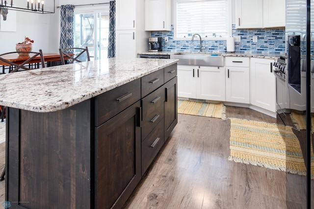 kitchen featuring light hardwood / wood-style floors, sink, white cabinets, a kitchen island, and decorative backsplash