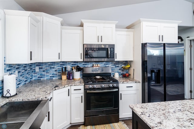 kitchen with appliances with stainless steel finishes, decorative backsplash, vaulted ceiling, white cabinets, and dark hardwood / wood-style floors