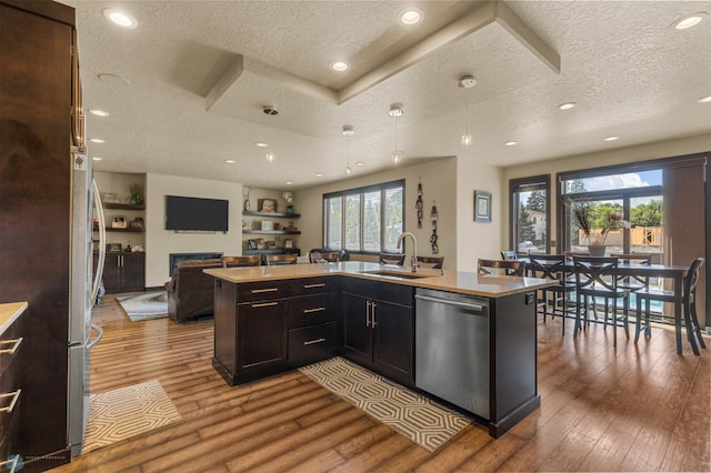 kitchen with a textured ceiling, stainless steel dishwasher, sink, and light hardwood / wood-style floors