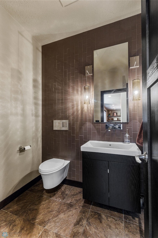 bathroom with vanity, toilet, tile walls, and a textured ceiling