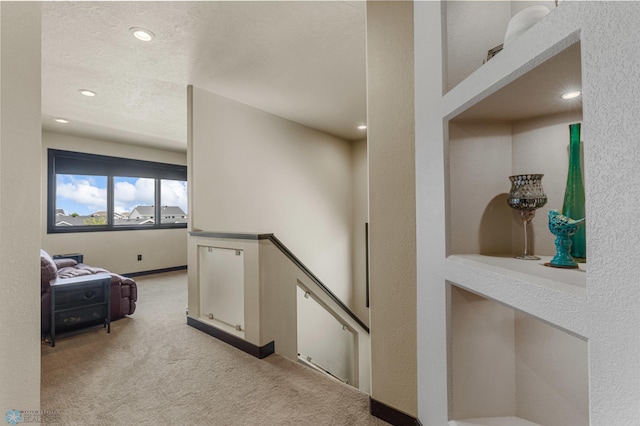 corridor with light carpet and a textured ceiling