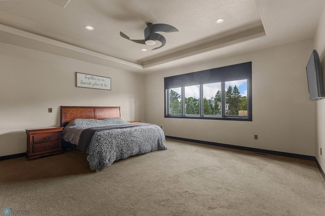 bedroom featuring ceiling fan, a raised ceiling, a textured ceiling, and carpet floors