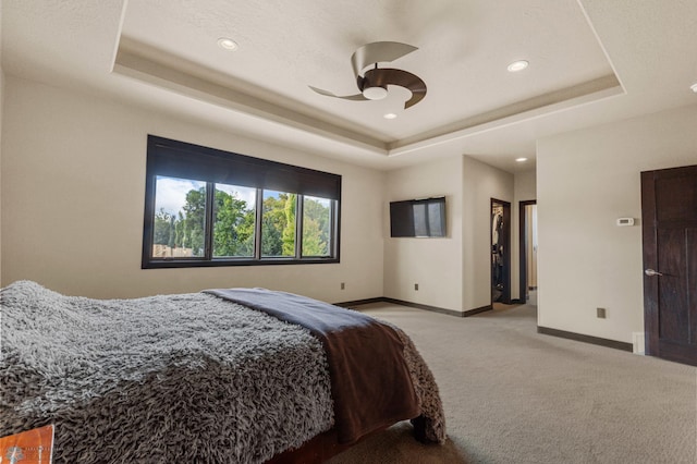 carpeted bedroom with a tray ceiling and ceiling fan