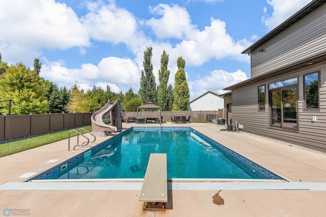 view of swimming pool with a water slide, a diving board, and a patio area