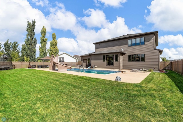 rear view of property featuring a fenced in pool, a lawn, and a patio