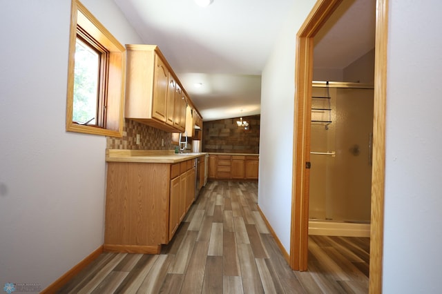 kitchen featuring lofted ceiling, hardwood / wood-style flooring, backsplash, and light brown cabinets