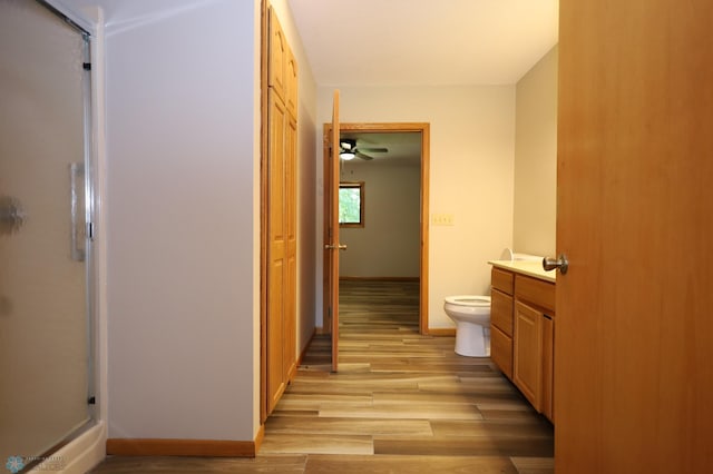 bathroom with toilet, a shower with door, vanity, ceiling fan, and hardwood / wood-style flooring