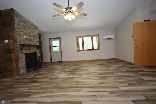 unfurnished living room featuring a wall mounted AC, vaulted ceiling, a fireplace, wood-type flooring, and ceiling fan