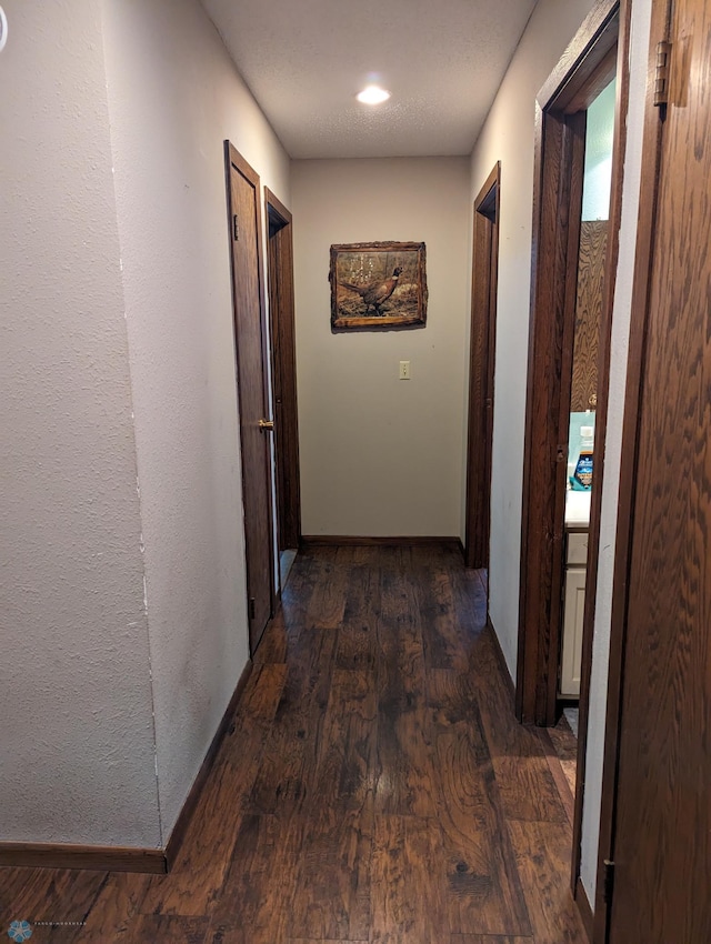 hall with dark hardwood / wood-style floors and a textured ceiling