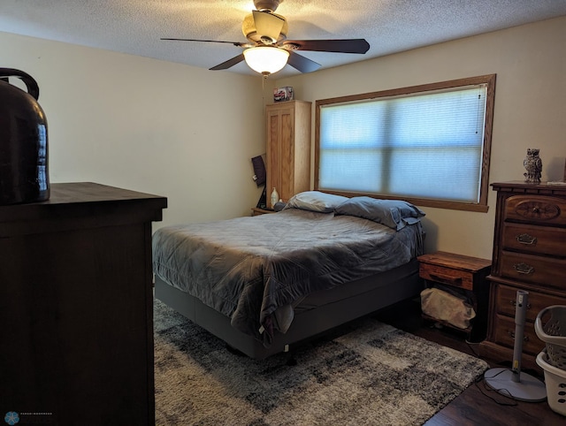 bedroom with ceiling fan, hardwood / wood-style flooring, and a textured ceiling