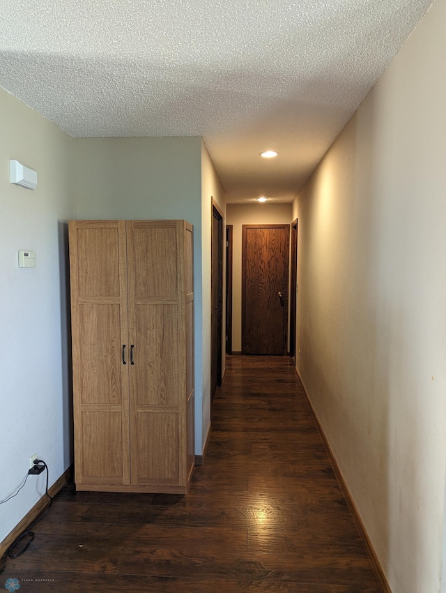 hallway featuring dark wood-type flooring and a textured ceiling