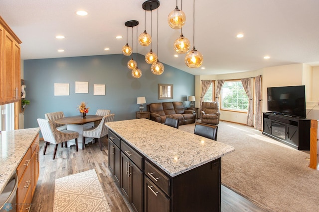 kitchen with pendant lighting, light hardwood / wood-style floors, lofted ceiling, a kitchen island, and dark brown cabinetry