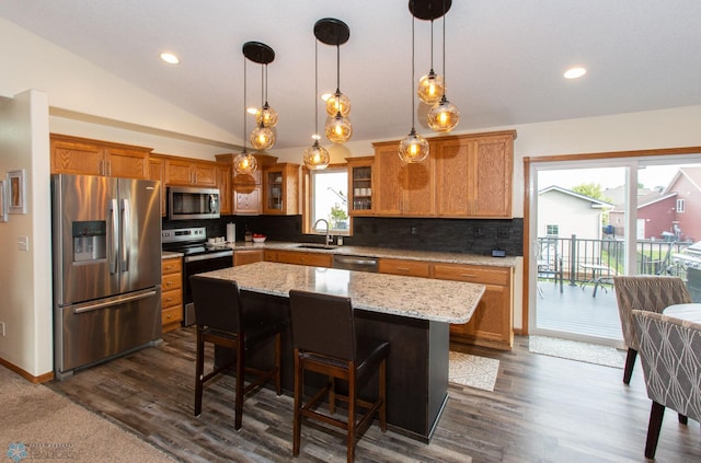 kitchen featuring vaulted ceiling, a center island, stainless steel appliances, and plenty of natural light