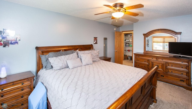 bedroom with ceiling fan, light colored carpet, and a textured ceiling