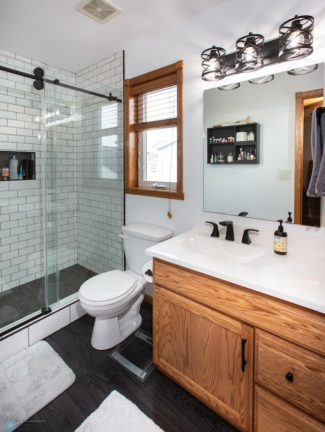 bathroom featuring hardwood / wood-style floors, vanity, toilet, and a shower with shower door