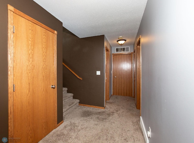 corridor featuring light colored carpet and a textured ceiling