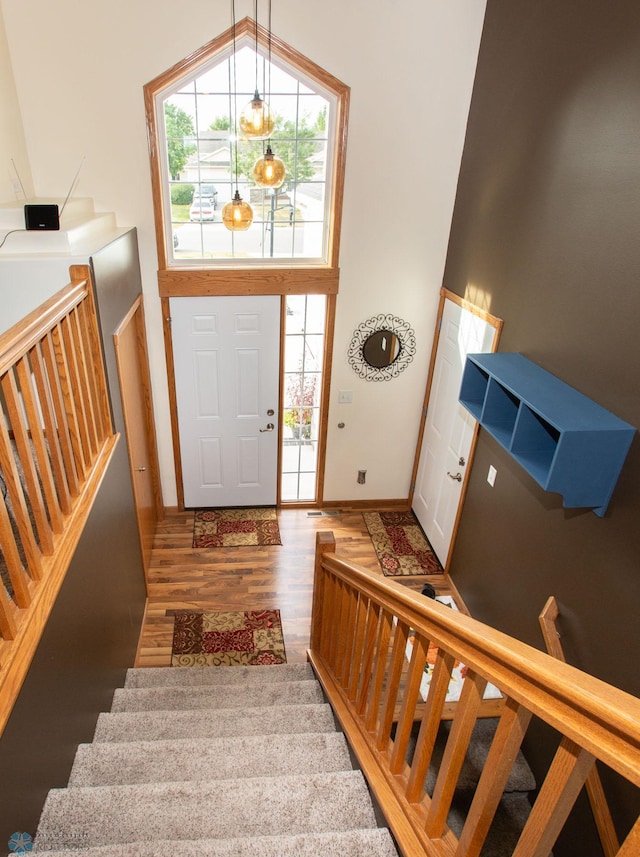 entrance foyer with a towering ceiling, dark hardwood / wood-style flooring, a chandelier, and plenty of natural light