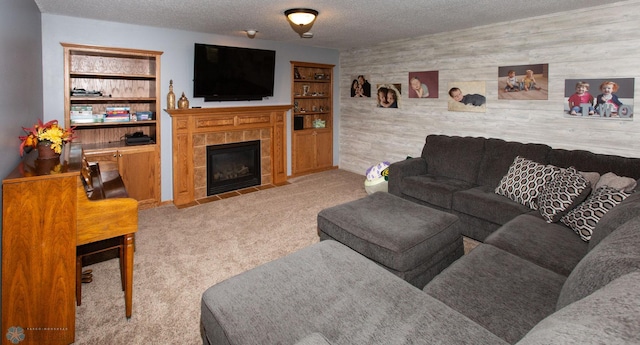 carpeted living room featuring a textured ceiling, wooden walls, and a tiled fireplace