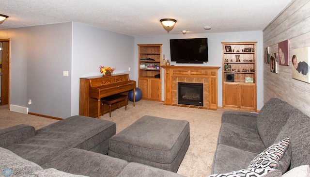 carpeted living room featuring a textured ceiling, a tiled fireplace, and wood walls