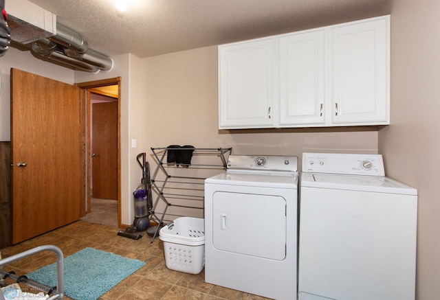 laundry area with cabinets, a textured ceiling, and washer and clothes dryer