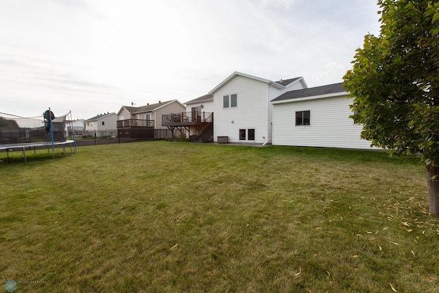 view of yard featuring a trampoline and a wooden deck