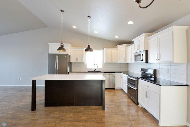 kitchen featuring tasteful backsplash, wood-type flooring, a center island, appliances with stainless steel finishes, and lofted ceiling