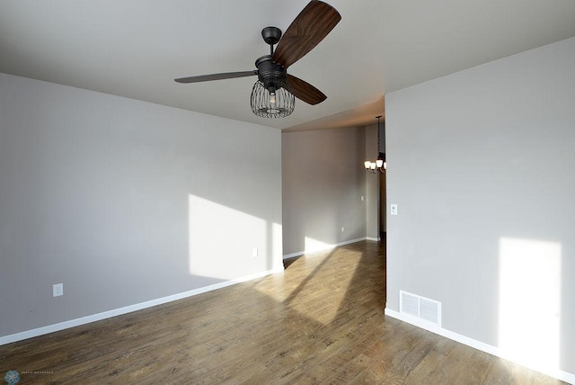 spare room featuring ceiling fan with notable chandelier and wood-type flooring